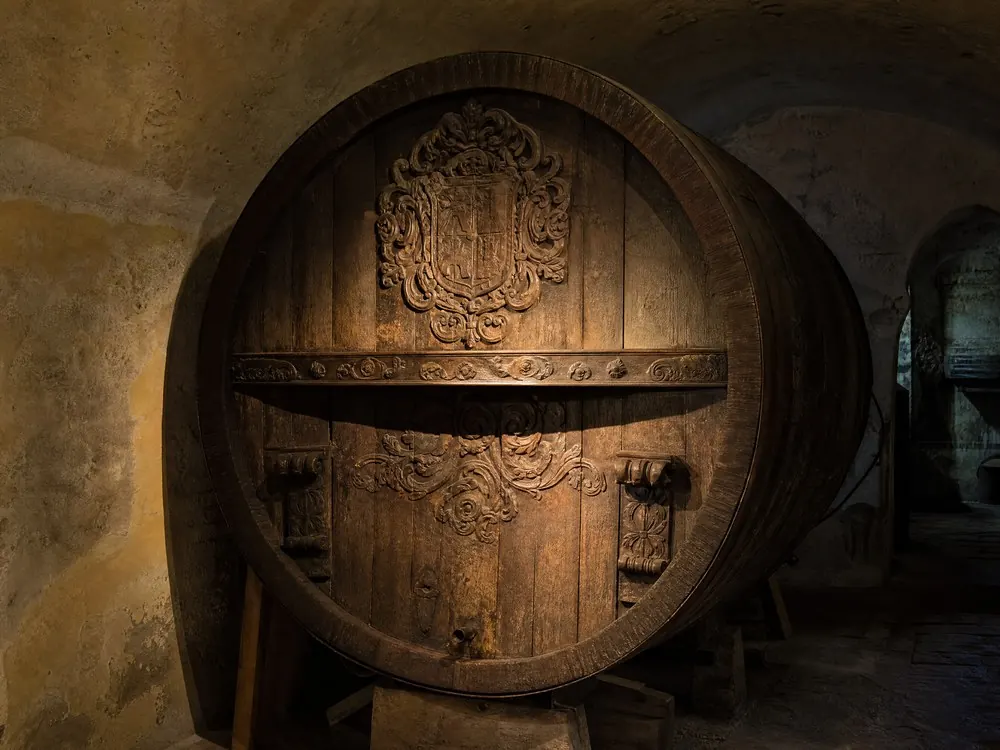 The carved end of a great oak cask in a cellar
